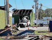  ??  ?? Workers restore power to damaged businesses Sunday near Norman.