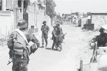  ??  ?? Iraqi government forces advance down a street in the Saqlawiyah area, north west of Fallujah, during an operation to regain control of the area from the Islamic State group. — AFP photo