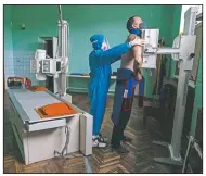  ?? (AP/Evgeniy Maloletka) ?? A medic prepares a coronaviru­s patient for a lung X-ray.