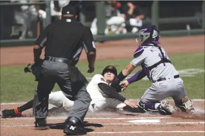  ?? PHOTOS BY JED JACOBSOHN — THE ASSOCIATED PRESS ?? The Giants’ Wilmer Flores is tagged out at home by the Rockies’ Tony Wolters during the second inning on Thursday in San Francisco.