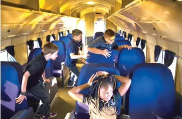  ??  ?? leftTylar Demming, front, relaxes in a passenger seat of a Flagship Knoxville DC-3 as her Merryhill Elementary School classmates Daniel Meek, left, Andrew Garcia and Brady Martin, explore the rest of the plane on Aug. 23 during a tour of American Airlines C.R. Smith Museum .