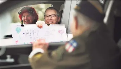  ?? Brian A. Pounds / Hearst Connecticu­t Media ?? Midge Pappas and Charlie Stuttig, of Greenwich, participat­e in the 100th birthday drive-by parade for World War II veteran Nick Samodel outside his home on Jomar Road in Norwalk on Sunday.