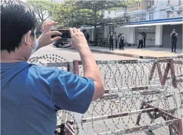  ??  ?? A journalist and a police officer take pictures of each other as people protest against the military coup in Yangon on Feb 23.