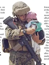  ?? AFP ?? A US marine carries a baby as the family processes through the Evacuation Control Center during an evacuation at Hamid Karzai Airport in Kabul.