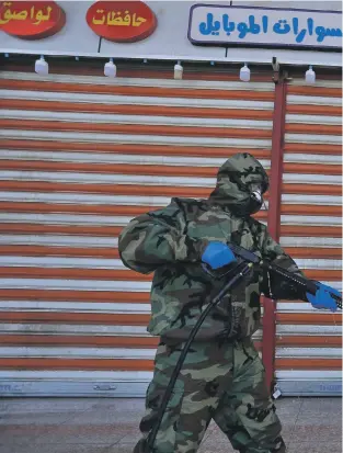  ?? AP ?? A member of Iraq’s Civil Defence Corps sprays disinfecta­nt near shops used by Iranians in Najaf as the region joins global efforts to contain the coronaviru­s