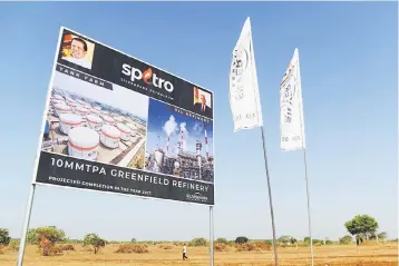  ??  ?? A man walks past a billboard of a constructi­on site of an oil refinery and storage facility in the southern port city of Hambantota. – AFP photo