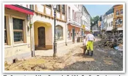  ??  ?? The German town of Ahrweiler was badly hit by flooding. Top, damaged bridge is torn down; above, a man uses a wheelbarro­w to move debris.