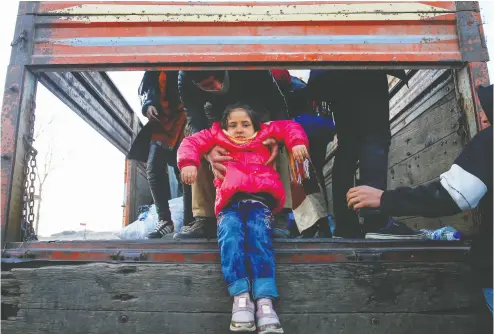  ?? Hus eyin Aldemir / Reuters ?? A migrant child is passed from a truck Tuesday near Turkey’s Pazarkule border crossing with Greece’s Kastanies,
near Edirne, Turkey. Ankara says it will no longer stop migrants who want to reach Europe.