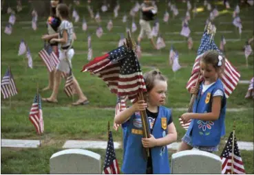  ?? KATIE GREENE — THE GRAND RAPIDS PRESS VIA AP ?? Natalie Benson, 5, and Holly Sweezer, 6, carry extra flags as Boy and Girl Scouts place flags on each of the 5,000 headstones at the Grand Rapids Veterans State Cemetery in Grand Rapids, Mich. The Wednesday Boy Scouts of America announceme­nt to admit...