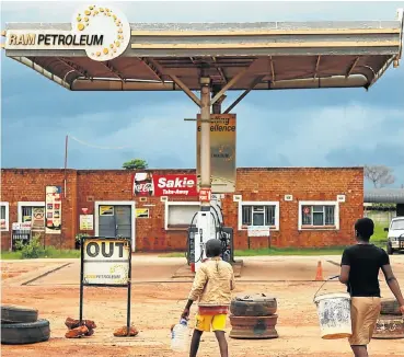  ?? Picture: Reuters ?? Children walk past a petrol station closed after protests in Harare. The fuel price has been hiked 150%.