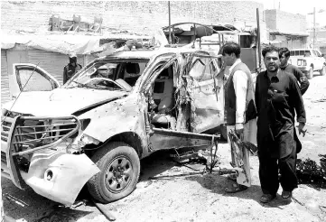  ?? — Reuters photo ?? Police and security personnel stand next to a damaged police vehicle after a blast in Chaman, Pakistan.