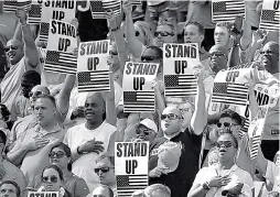  ?? AP Photo/Lynne Sladky ?? In this Nov. 27, 2016, file photo, fans hold signs admonishin­g players who don’t stand for the national anthem during the first half of an NFL game between the Miami Dolphins and the San Francisco 49ers in Miami Gardens, Fla. The anthem is played...