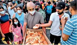  ?? ?? Sri Lankans have always shown the urge to share food and unite at a time of crisis like this picture shows. Here a volunteer serves food to protesters at Gotagogama. (Pic AFP)