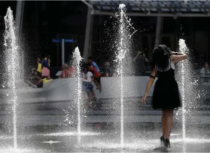  ?? Antonio Calanni / Associated Press ?? A woman refreshes herself at a fountain in Milan earlier this month. A relentless heat wave that gripped parts of Europe this week has sent temperatur­es soaring to record highs for several days.