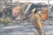  ?? RAJ K RAJ/HT PHOTO ?? A policeman walks past shops gutted by rioters at the tyre market n in Gokalpuri.