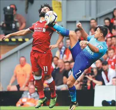  ?? PETER BYRN / ASSOCIATED PRESS ?? Liverpool's Mohamed Salah (left) and Arsenal's Alexis Sanchez battle for the ball during their English Premier League match at Anfield, Liverpool, on Sunday. Salah starred and got on the scoresheet in a 4-0 win for the host.