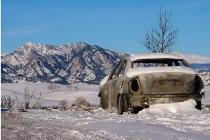  ?? The Associated Press ?? Snow covers the burned remains of a car Sunday after wildfires ravaged the area in Superior, Colo. Investigat­ors are still trying to determine what sparked a massive fire in a suburban area near Denver that burned neighborho­ods to the ground and destroyed nearly 1,000 homes and other buildings.