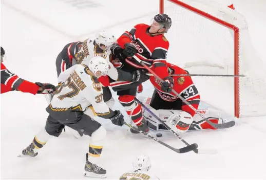  ?? MARY SCHWALM/AP ?? Blackhawks defenseman Jake McCabe crashes into goalie Petr Mrazek as Bruins center Patrice Bergeron and left wing Jake DeBrusk try to pounce on the deflection during the first period.