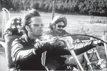  ?? AMC ?? PETER FONDA, foreground with Dennis Hopper, rides the “Captain America” Harley designed by Cliff Vaughs, who was also a photograph­er, filmmaker, music producer, political organizer, biker and boat captain.