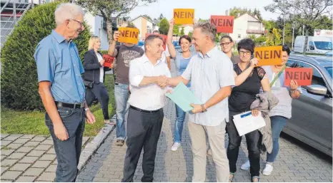 ?? FOTO: PATRICK LAABS ?? Patrick Szilagyi übergibt vor der Gemeindera­tssitzung rund 600 Unterschri­ften an Bürgermeis­ter Spieß. Damit wollen die Bürger noch einmal für den Erhalt der Gögginger Grundschul­e kämpfen.