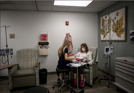  ?? AARON ONTIVEROZ — THE DENVER POST ?? Chelsey Baker- Hauck receives an intravenou­s treatment from nurse Lyndsey Richards to treat the symptoms of her long COVID at Cancer Centers of Colorado. “Everybody’s moving on from COVID, but there’s a huge population of people like me who can’t and may never be able to,” she said.