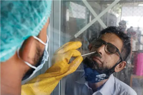  ?? (Akhtar Soomro/Reuters) ?? A PARAMEDIC wearing protective gloves takes a noseswab sample to be tested for the coronaviru­s disease, in Karachi, Pakistan.