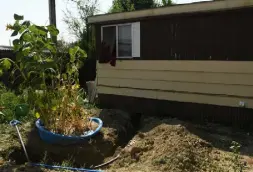  ??  ?? Nate and Melissa Webb have a ditch outside their home after a crew worked on the water lines at the Central Manufactur­ed Home Community.