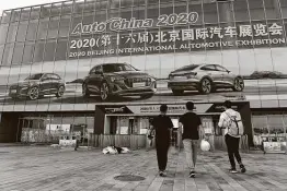  ?? Greg Baker / AFP via Getty Images ?? Workers walk into an exhibition hall last week during preparatio­ns for the Beijing Internatio­nal Automotive Exhibition. It’s the world’s first major auto show since the coronaviru­s outbreak.