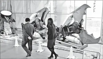  ??  ?? Visitors look at gigantic scissors for cutting steel beams and reinforcin­g bars, or crushing a mass of concrete at the “Kojichu!” exhibition.