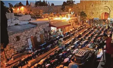  ??  ?? MUSLIM Palestin menunaikan solat Maghrib
di pintu masuk pekarangan Masjid Al-Aqsa, kelmarin. - EPA