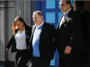  ?? MARK KAUZLARICH / BLOOMBERG ?? Movie mogul Harvey Weinstein is escorted in handcuffs Friday after surrenderi­ng to face charges of rape and sexual abuse in assault cases involving two women.