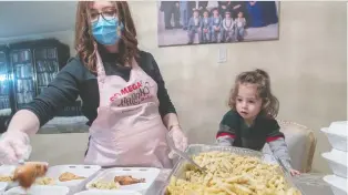  ?? DAVE SIDAWAY ?? Yosef, 18 months, keeps an eye on mom, Chaya Raskin Naparstek, filling meal containers for seniors in Côte-st-luc. Hot meals are prepared and delivered by volunteers to about 75 seniors every Wednesday.