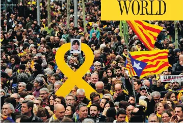  ?? LLUIS GENE / AFP / GETTY IMAGES ?? Protesters hold a yellow ribbon with a picture of Catalonia’s deposed leader Carles Puigdemont while waving Catalan pro-independen­ce Estelada flags during a demonstrat­ion in Barcelona on Sunday.