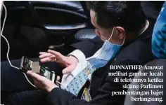  ??  ?? RONNATHEP Anuwat melihat gambar lucah di telefonnya ketika sidang Parlimen pembentang­an bajet berlangsun­g.