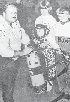  ?? FILE ?? In 1993, Randy Neily, an instructor at the Nova Scotia Fire Fighting School in Waverly, visited schoolchil­dren in Falmouth to demonstrat­e what firefighte­rs’ equipment is used for. Pictured with him are Lindsay Ferguson and Billy Hines.