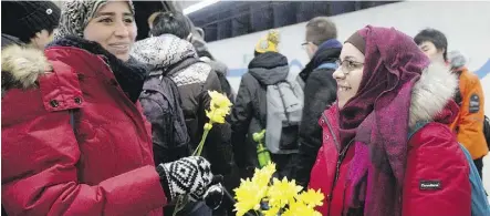  ?? DAVID BLOOM ?? Nakita Valerio, right, hands out flowers to women wearing hijabs at the U of A LRT station in December. In November, a man threatened two Muslim women at the LRT station with a noose.