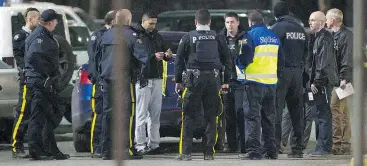  ?? GERRY KAHRMANN/PNG ?? Police gather as they investigat­e the shooting of a Transit Police officer at the Scott Rd Station in Surrey on Wednesday. The suspect was not found.