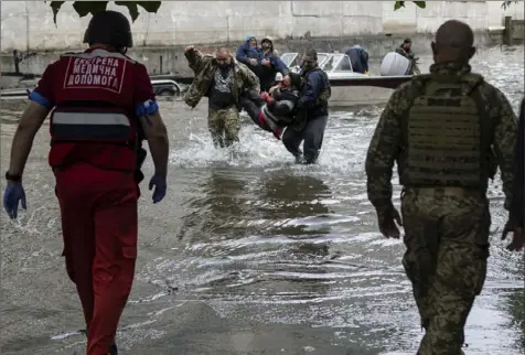  ?? Associated Press ?? Emergency teams help rush to safety injured civilian evacuees who had came under fire from Russian forces while trying to flee by boat from the Russian-occupied east bank of a flooded Dnieper River to Ukrainian-held Kherson, on the western bank in Kherson, Ukraine, on Sunday.