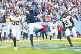  ?? AP PHOTO/JOHN AMIS ?? Tennessee Titans wide receiver DeAndre Hopkins (10) catches a touchdown pass against Jacksonvil­le Jaguars cornerback Tyson Campbell (32) and Rayshawn Jenkins (2) during the regular-season finale for both teams Sunday in Nashville.