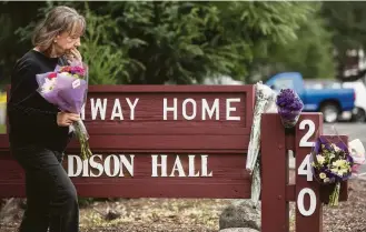  ?? Jessica Christian / Associated Press ?? A woman leaves a bouquet of flowers on Saturday following the deadly shooting of three female employees by a former resident at a veterans home in Yountville, Calif.