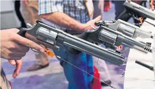  ?? ETHAN MILLER/GETTY IMAGES ?? Convention attendees try out handguns at the Smith & Wesson booth at the 2018 National Shooting Sports Foundation’s Shooting, Hunting, Outdoor Trade Show earlier this year in Las Vegas, Nev.