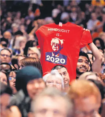  ?? FOTO: AFP ?? Ein Anhänger von Bernie Sanders hält ein T-Shirt mit dem Konterfei des amerikanis­chen Senators in die Luft. Auf dem Shirt steht das Sprichwort „Hindsight is 20/20“. Es bedeutet übersetzt: „Hinterher ist man immer klüger“. Der Spruch ist doppeldeut­ig: 2020 steht die nächste US-Wahl an, bei der Sanders erneut kandidiere­n könnte. Der Ursprung des Spruchs liegt derweil in der Augenheilk­unde. Mit „20/20“meinen amerikanis­che Augenärzte die volle Sehkraft.