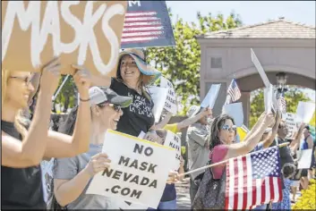  ??  ?? Protesters hold signs and chant slogans during a No Mask Nevada PAC rally along South Green Valley Parkway at Paseo Verde Parkway on Saturday in Henderson.