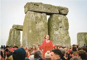  ?? FINNBARR WEBSTER/GETTY ?? Summer solstice: A woman breaks out in song Tuesday at Stonehenge in Wiltshire, England. Thousands of revelers greeted the solstice, the longest day of the year in the Northern Hemisphere. It was the first time revelers were permitted to gather for the solstice since 2019 because of the pandemic. Stonehenge was built 3,500 to 5,000 years ago.