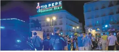  ?? LUCA PIERGIOVAN­NI / EFE ?? Un policía local de Madrid observa a los jóvenes en la Puerta del Sol.