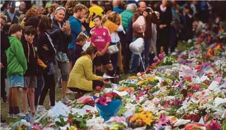  ?? AFP PIC ?? People paying their last respects to victims of the Christchur­ch shooting at a memorial site at the Botanical Garden in Christchur­ch yesterday.