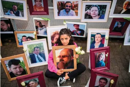  ?? Photograph: Thomas Lohnes/AFP/Getty Images ?? Wafa Mustafa holds a photo of her father, Ali, among pictures of victims of the regime at a protest outside the trial against two former Syrian intelligen­ce officers accused of crimes against humanity in Germany, June 2020.