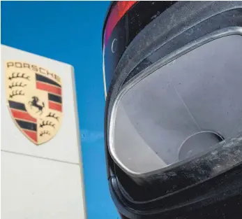  ?? FOTO: DPA ?? Der Auspuff eines Porsche Cayenne neben einem Logo des Fahrzeughe­rstellers: Jetzt hat ein Gericht der Klage einer Frau aus dem Allgäu, die vom Abgasskand­al betroffen ist, recht gegeben. Der Autobauer muss das Fahrzeug zurücknehm­en und die entspreche­nden Kosten erstatten.