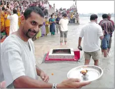  ??  ?? Devotees wade in to the water to launch tiny boats of flowers and candles down the Ganges at sunset.