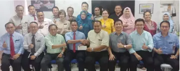  ??  ?? Aziz (seated fourth left) presents a RM50,000-cheque to MGBS Padawan District chairman Lawrence Steve Peter Muri on behalf of the council while others give the thumbs-up.